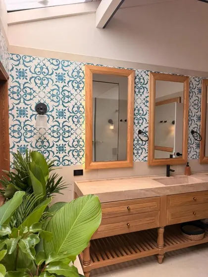 Baño de la Casa 105 con baldosa hidráulica azul, espejos con marco en madera y mueble de lavamanos en madera